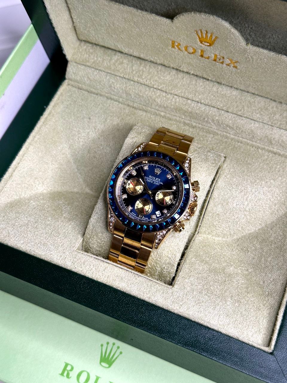 Rolex Cosmograph Daytona "Blue Gem / Sapphire Bezel" (Yellow Gold Edition) — Yellow Gold-Tone Stainless Steel Case with Blue Sapphire Baguette Bezel, Diamond-Set Lugs, Blue Sunburst Dial with Gold Sub-Dials, and Matching Gold-Tone Oyster Bracelet Hover